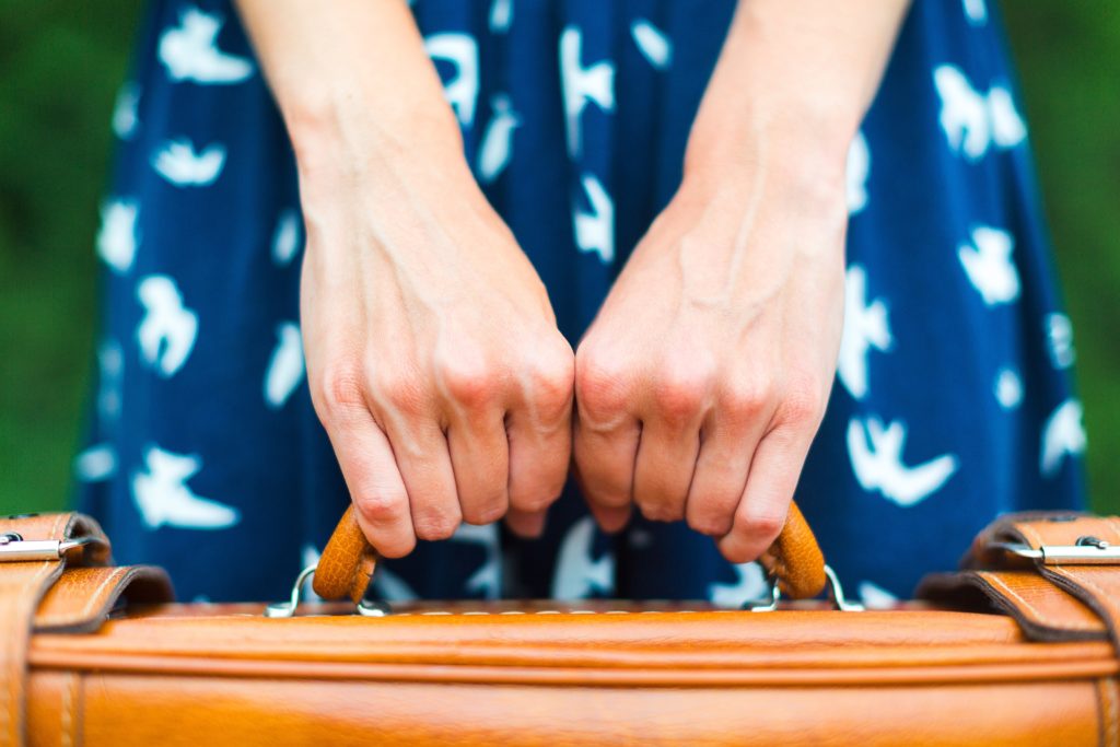 Image of hands holding a suitcase handle.